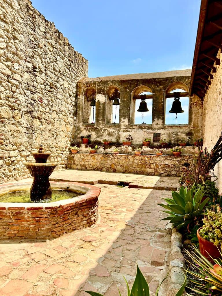 Bells hanging from arches in a courtyard of the historic mission at San Juan Capistrano.