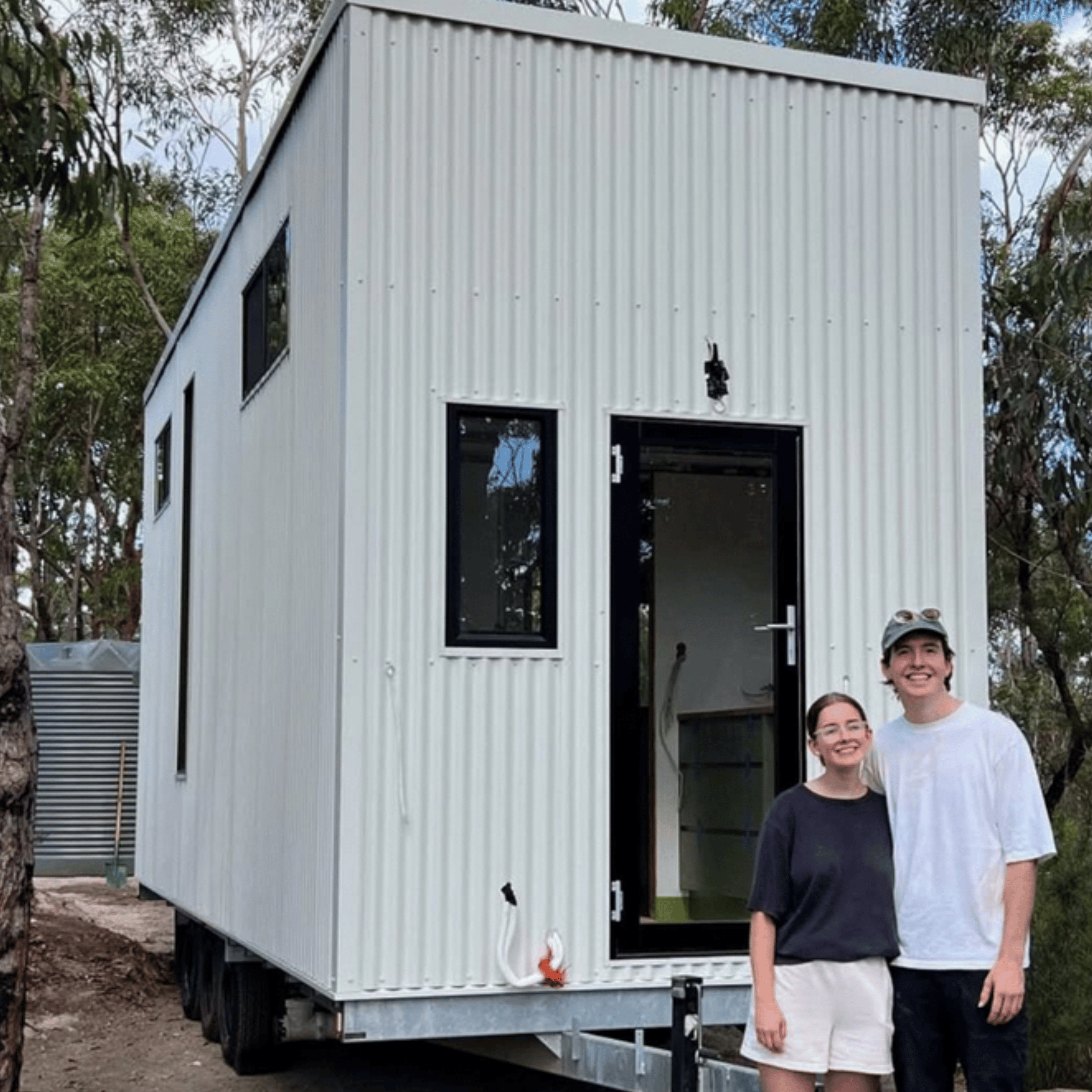 Young couple in front of DIY tiny house