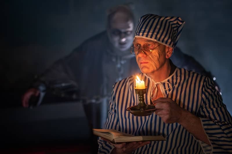 Ebenezer Scrooge holding a lit candle in his hand