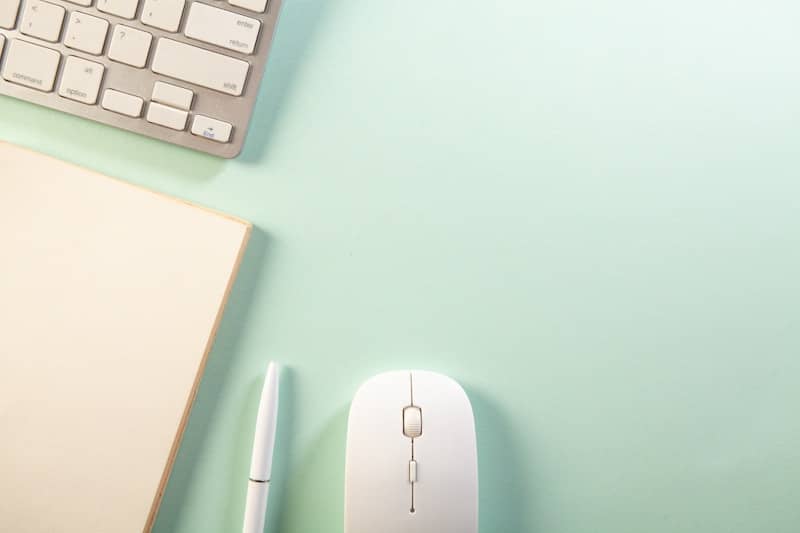 A keyboard, notebook, pen, and mouse on a desk