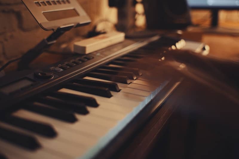 A person playing a digital keyboard in a dimly lit room with warm light