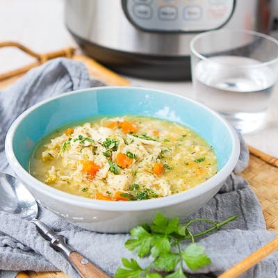 Chicken and rice soup in a blue bowl, with an Instant Pot behind.