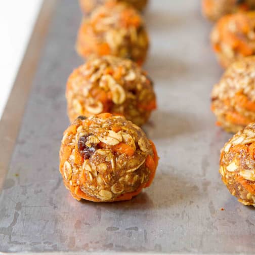 Carrot granola bites lined up on a baking sheet.