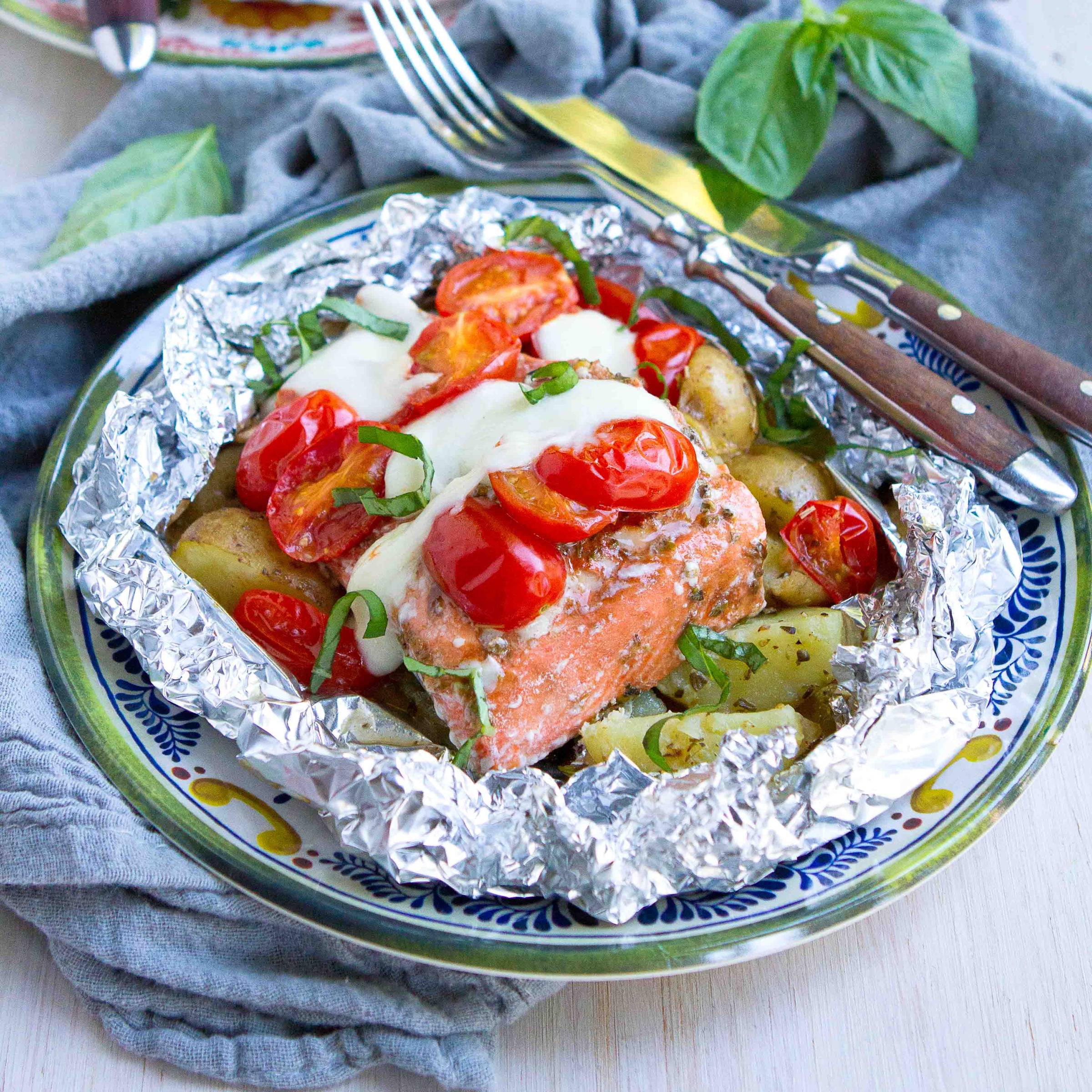 Salmon foil packets with melted cheese and tomatoes.