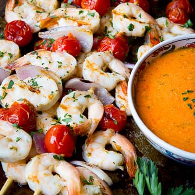 Shrimp and tomato kabobs with a side of red pepper sauce.