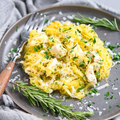 Spaghetti squash with chicken on a plate with rosemary sprigs.