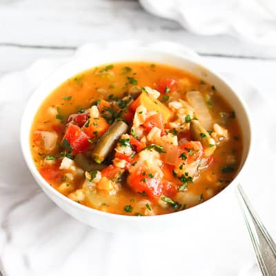 A white bowl filled with barley and vegetable soup.