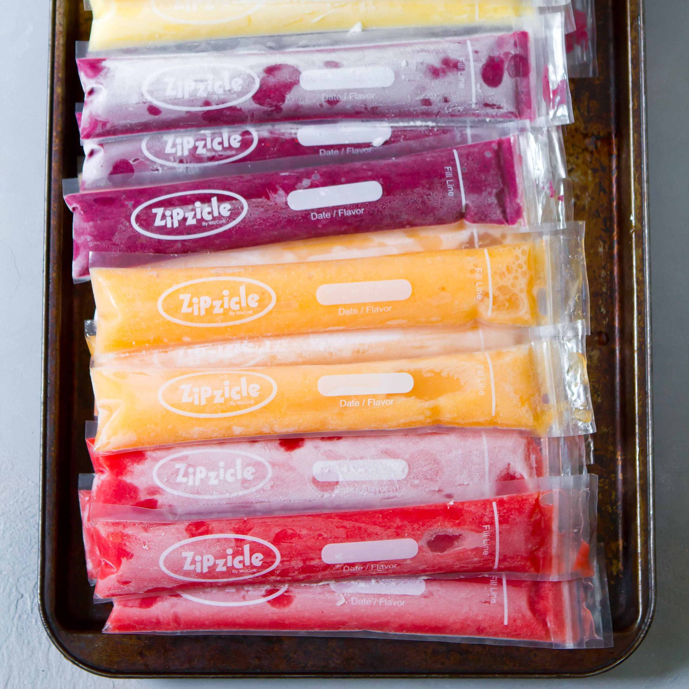 A variety of ice pops lined up on a baking sheet.