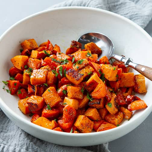 Roasted sweet potatoes and carrots in a white bowl.