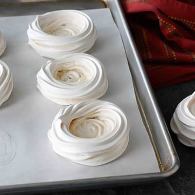 Meringue shells on a baking sheet.