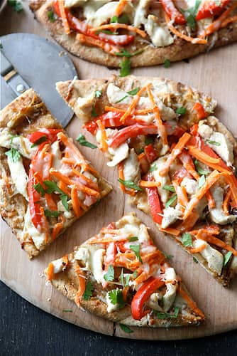 A quartered naan pizza topped with chicken and vegetables.