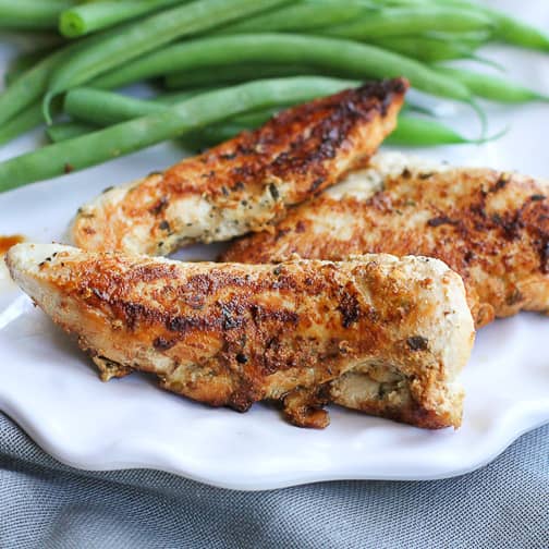 Cooked chicken tenders and green beans on a plate.