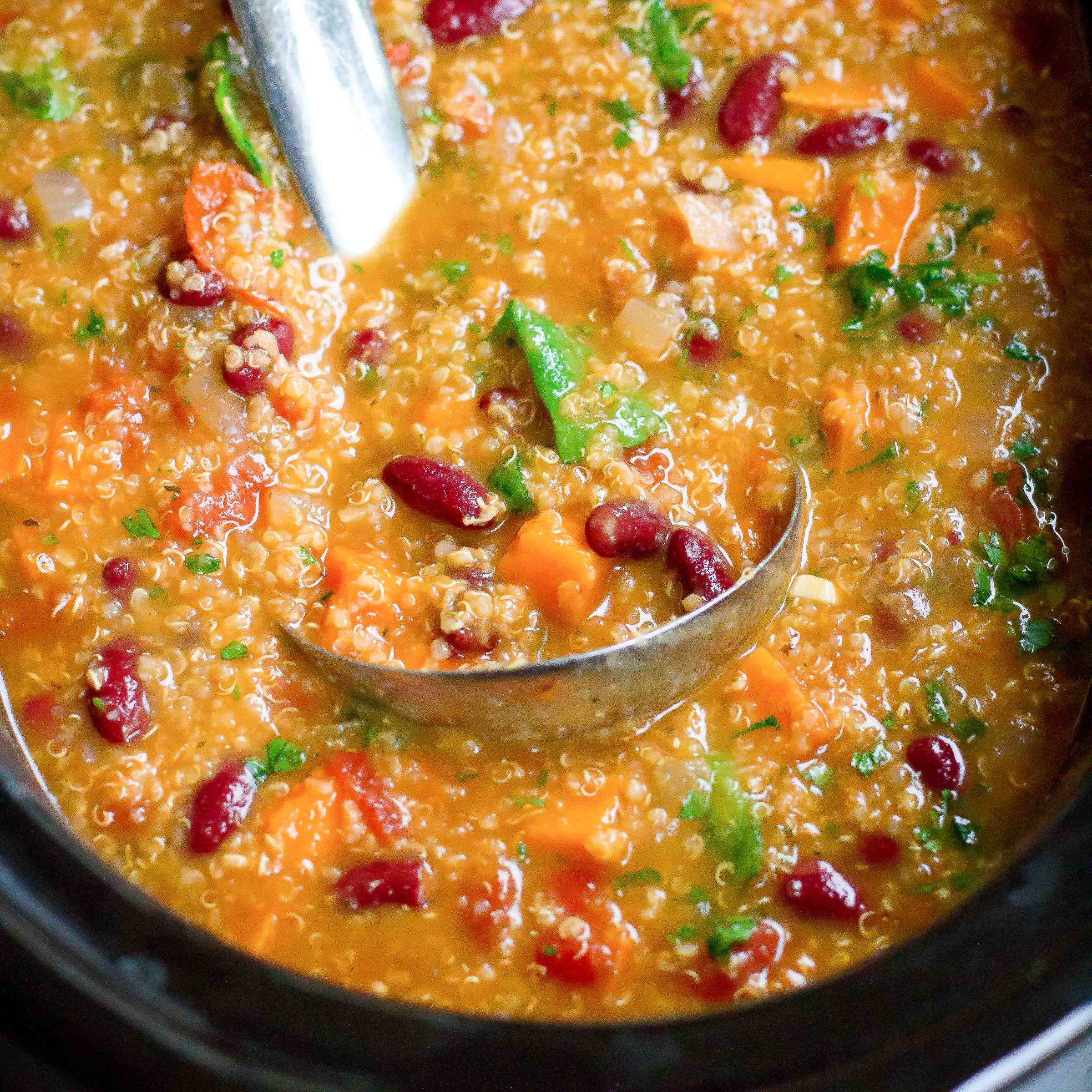 Soup with beans, sweet potato and quinoa with a ladle.