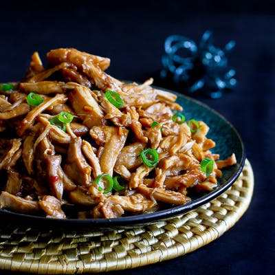 Shredded chicken in hoisin sauce piled on a blue plate.