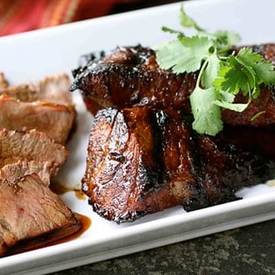 A cooked tri-tip steak on a white platter.