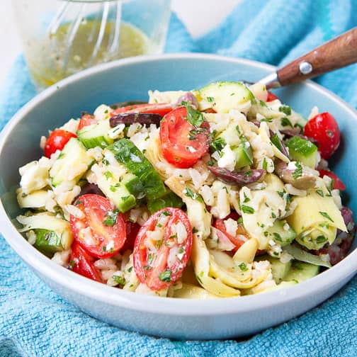 Rice salad with vegetables in a blue bowl.