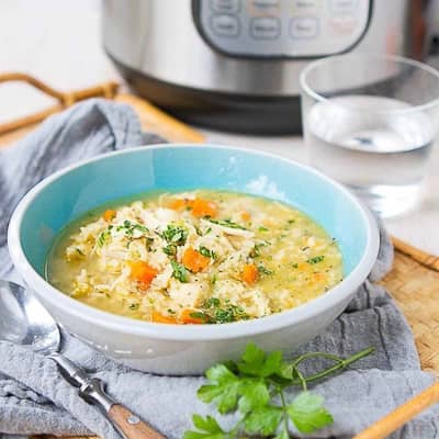 Chicken and rice soup in a blue and gray bowl.