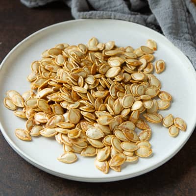 Cooked pumpkin seeds on a plate.