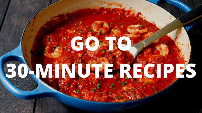 A large blue skillet with tomato sauce and shrimp.