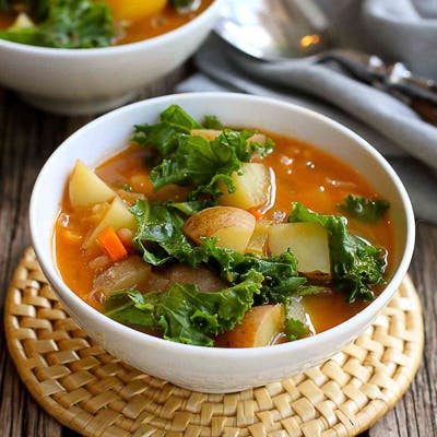Potato and kale soup in a white bowl.