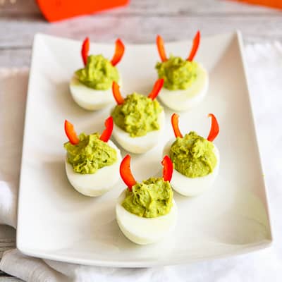 Green deviled eggs with red pepper horns.
