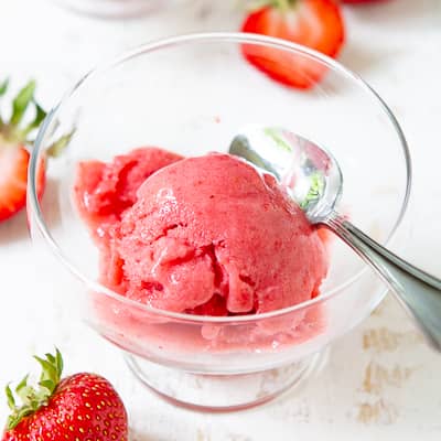 A scoop of strawberry nice cream in a glass bowl.