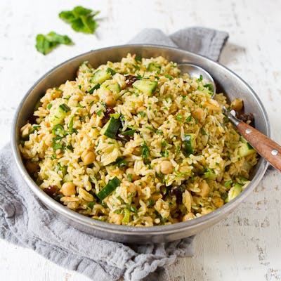 Rice salad with chickpeas and cucumber in a metal bowl.