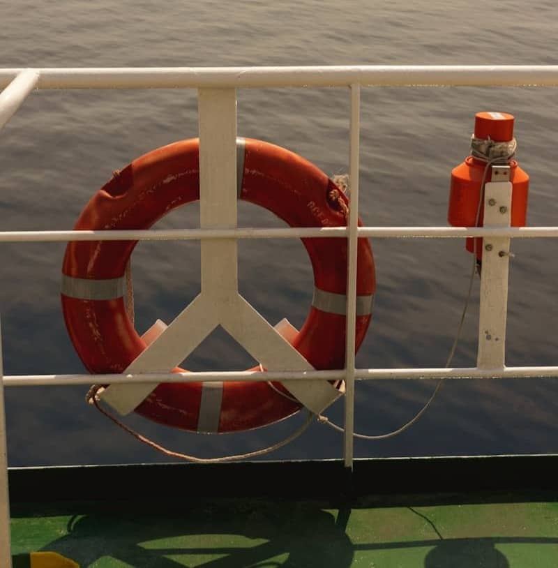 Orange life preserver on a ship railing over water