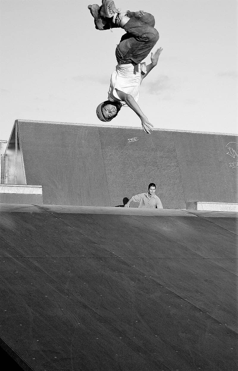 Skateboarder flips upside down mid-air at skatepark.