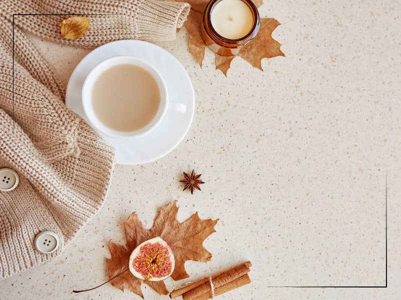 Fall-themed coffee, leaf, sweater on countertop