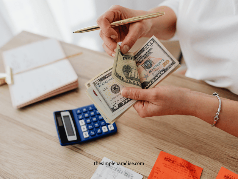 counting money at a table with book and calulator