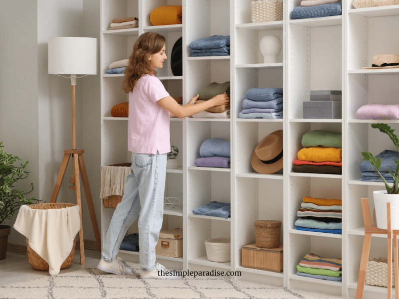 Woman organizing clothes on an open shelf unit
