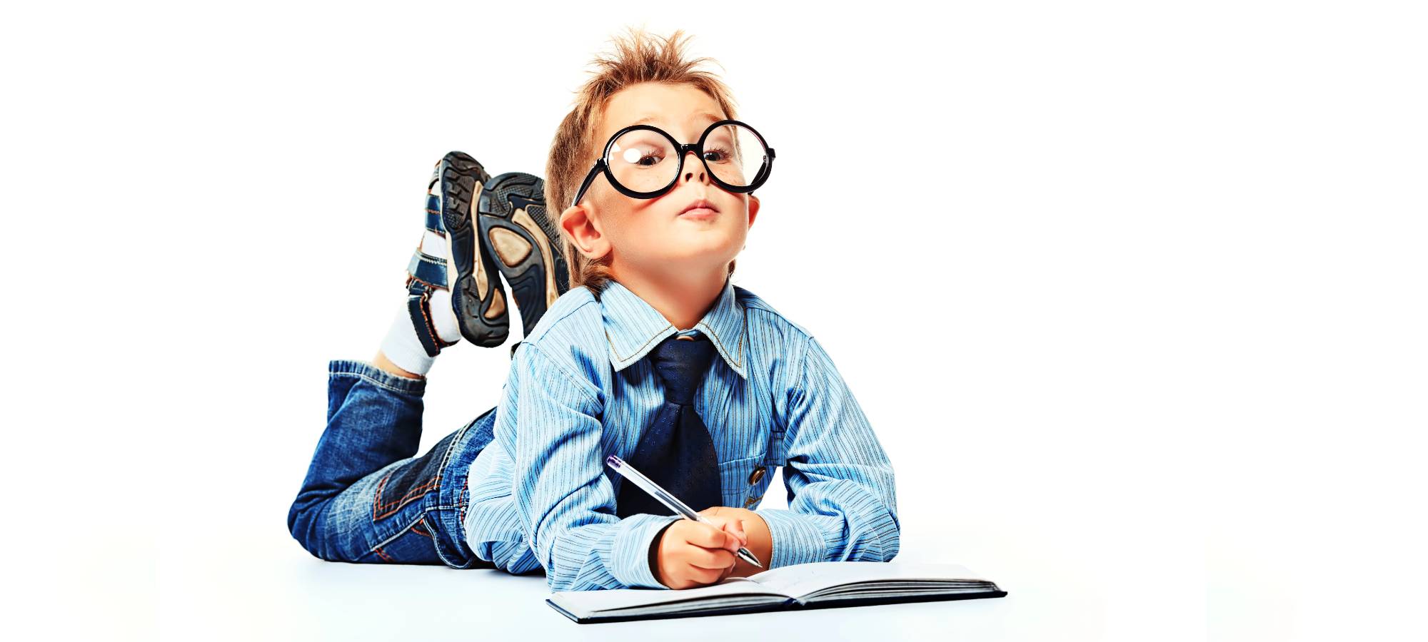 A young boy with glasses writing a notebook