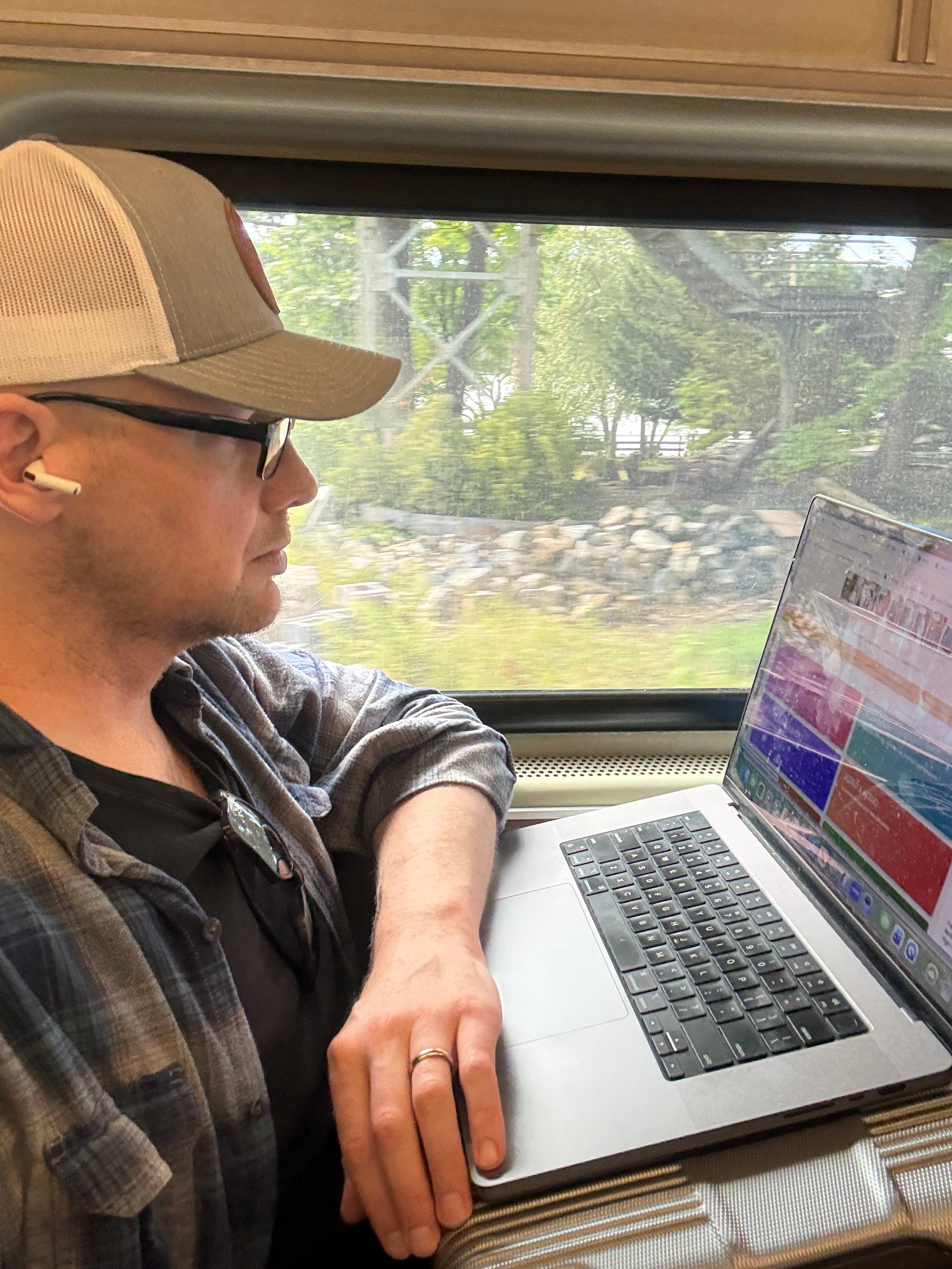 Lucas Van Engen working on his Actors Access profile on a laptop while riding a train.