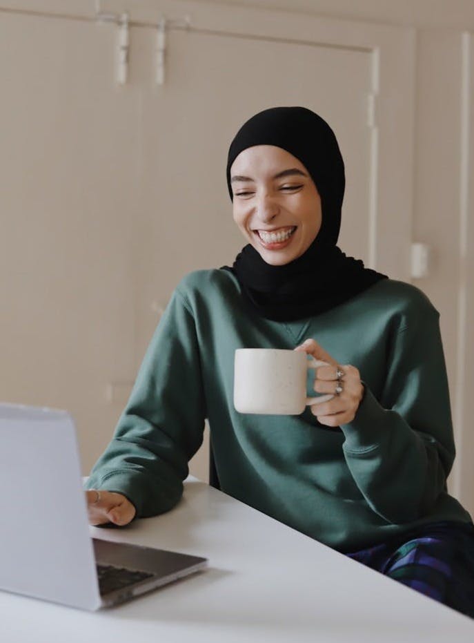 woman in green hijab holding white ceramic mug
