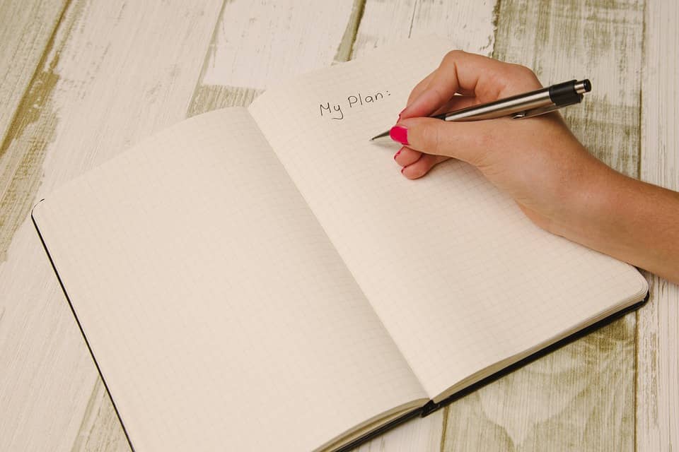 notebook on white wood board table w/hand writing "my plan"