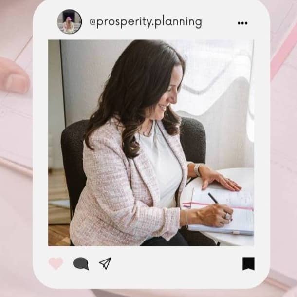 Woman in a soft pink blazer working at her desk with a notebook and laptop, representing intentional financial planning and budgeting.