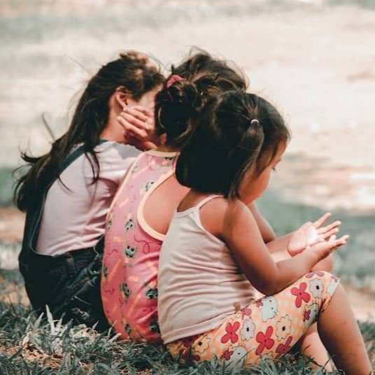 three children sitting on grass