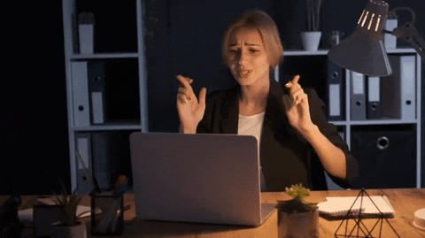 woman crossing fingers in front of laptop