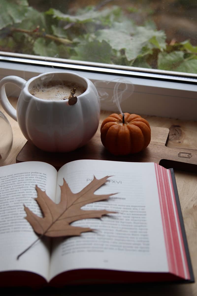 Cozy autumn scene with coffee, book, and pumpkin.