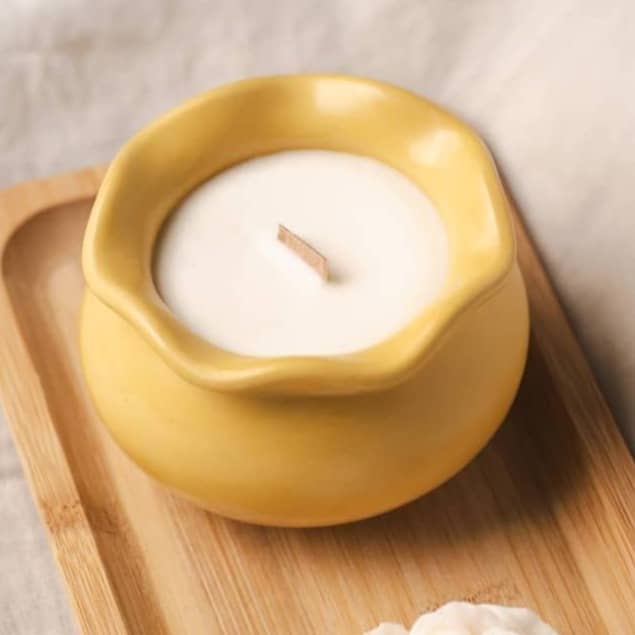 A yellow candle and rose sit on a tray.
