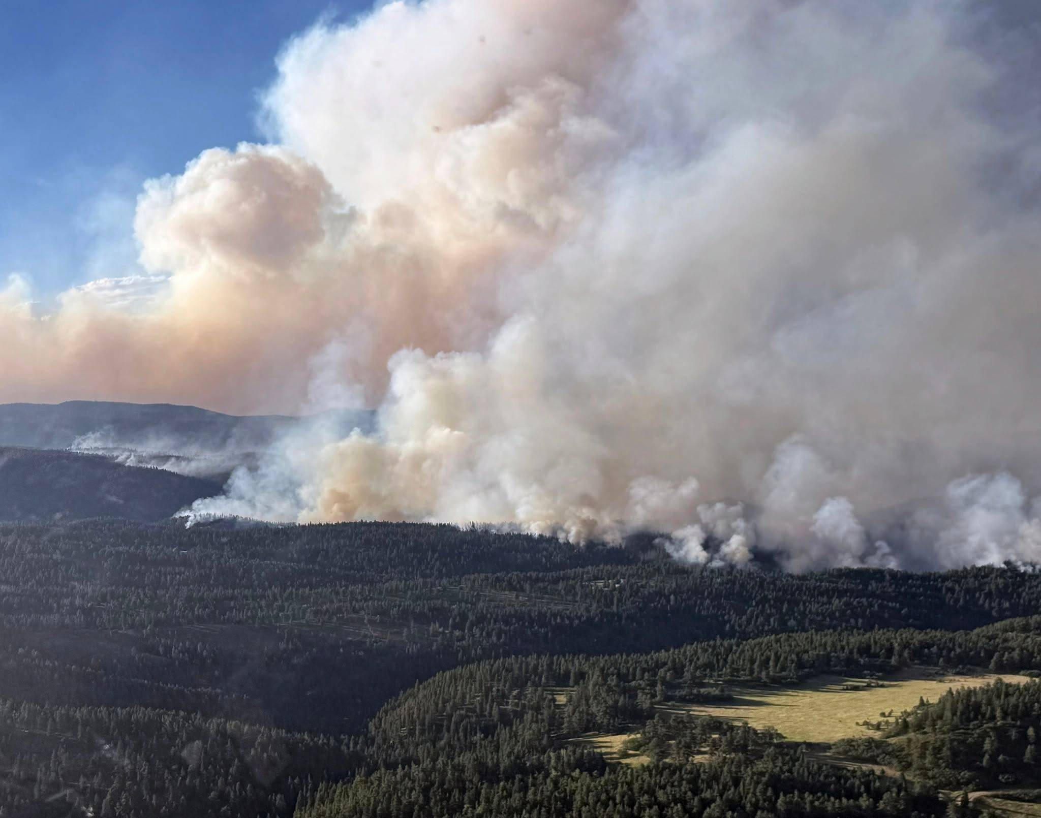 A wildfire with heavy smoke in a large area of forested land
