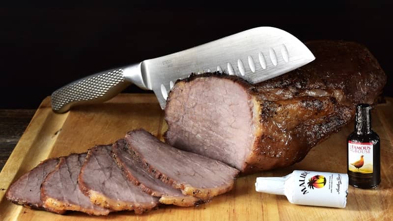 Sliced roasted meat with condiments on a cutting board.