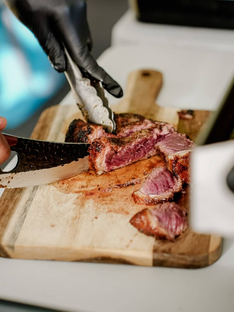 Chef slicing perfectly cooked steak on a wooden cutting board