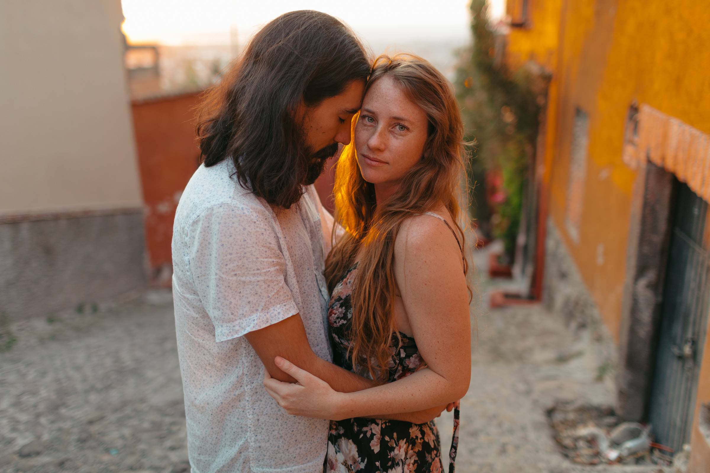 A photo of a beautiful couple embracing on a cobblestone street in San Miguel de Allende Mexico, at Sunset.