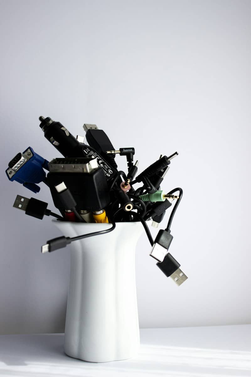Tangled electronic cables and adapters in a white vase