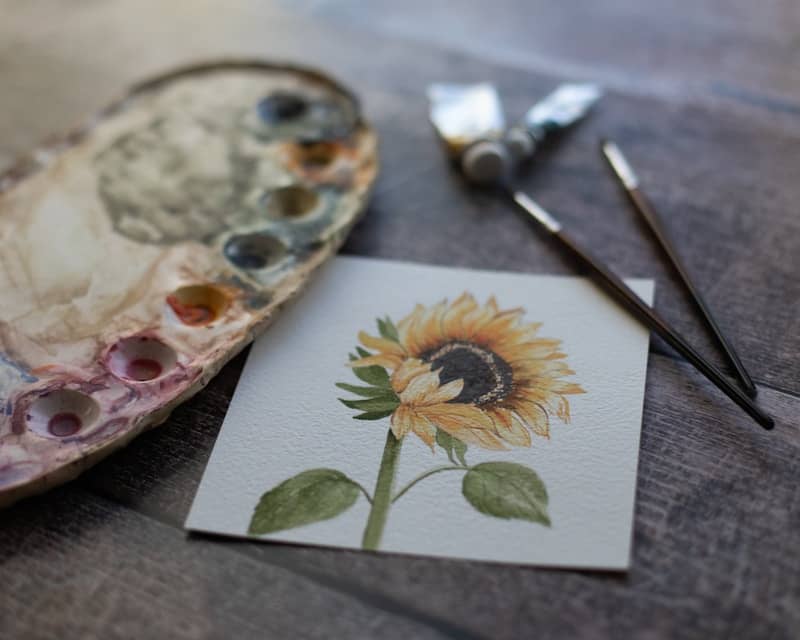 A sunflower painted on a piece of paper next to a pair of scissors