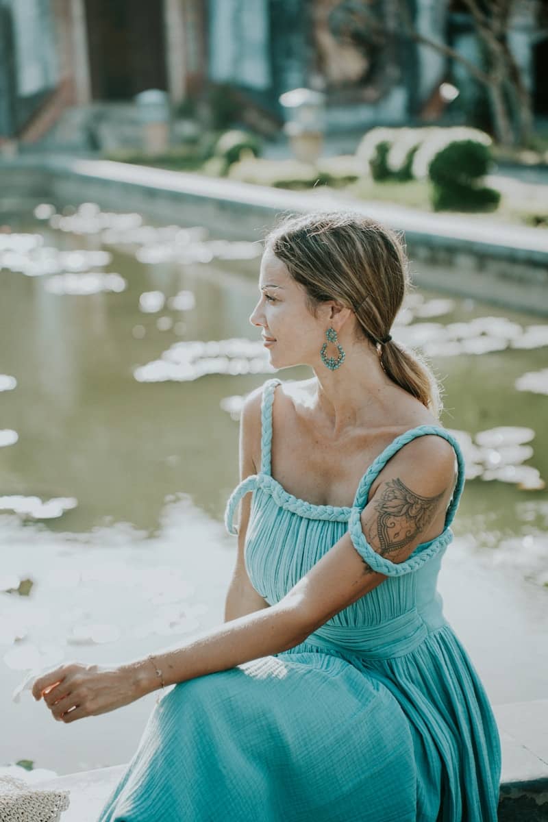 Woman in blue dress sitting by water