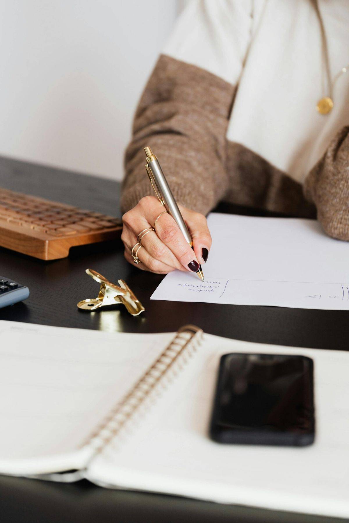 A person writing in a notebook with coffee.