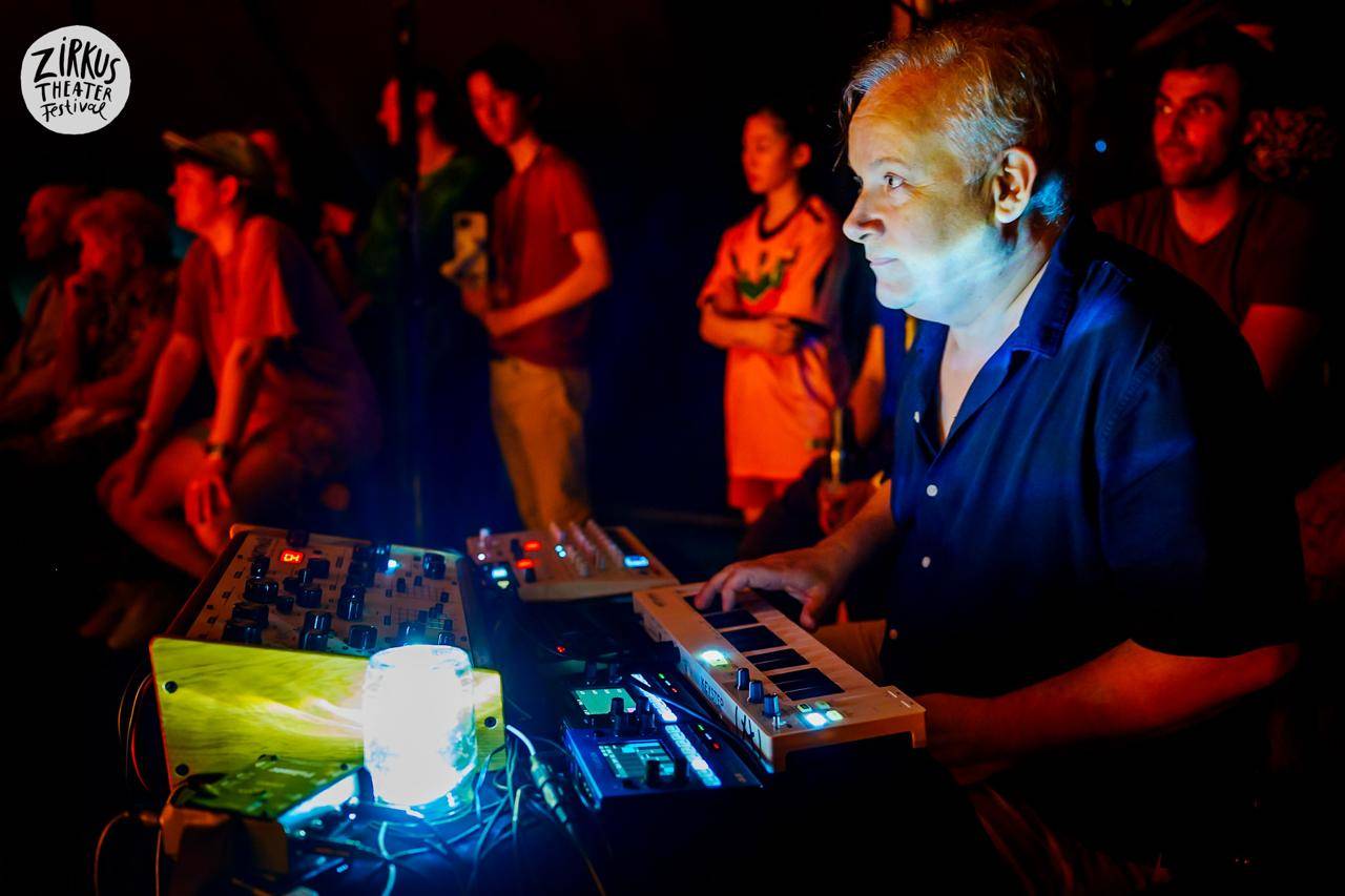 a musician, electronic music. People blurry in the background